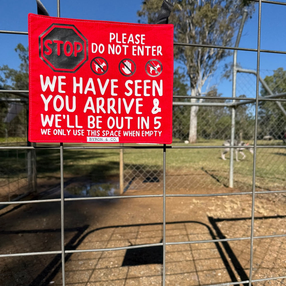 Red warning sign on a fence with text and symbols, outdoors.